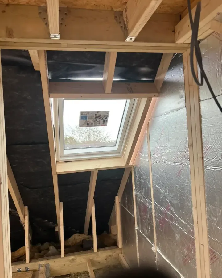 Foil-backed insulation fitted between timber framing around a new roof window